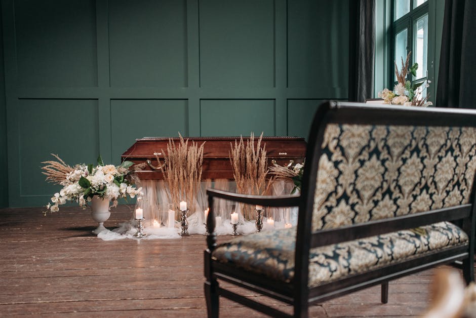 A wooden table decorated with floral arrangements and candles, positioned in a room with dark green paneled walls and natural light coming through large windows dressed with black curtains. On the lef